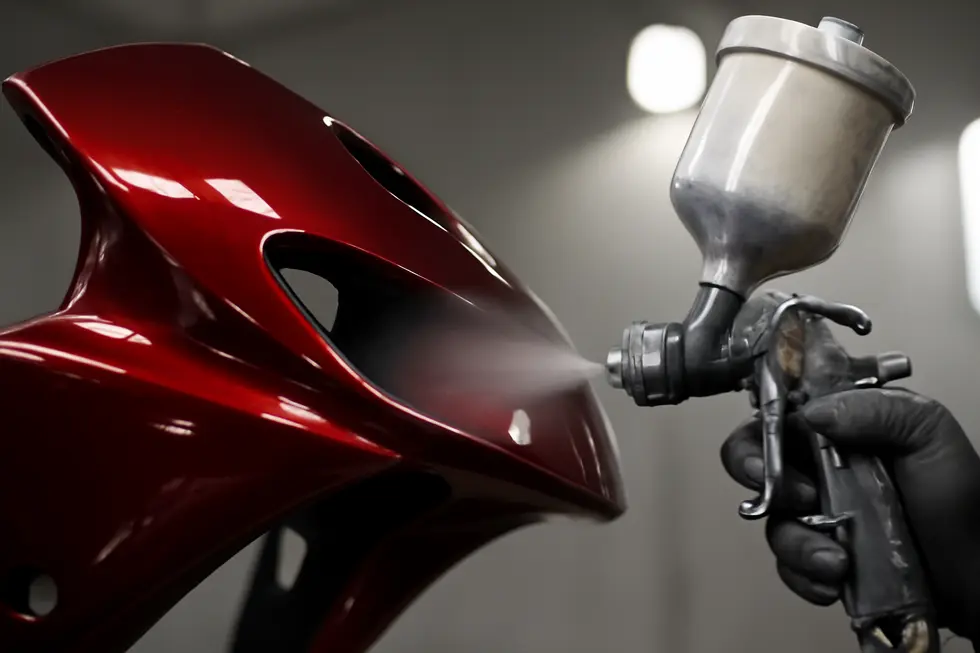 Different motorcycle fairing materials displayed on a workshop bench, showcasing the key substrates for painting.