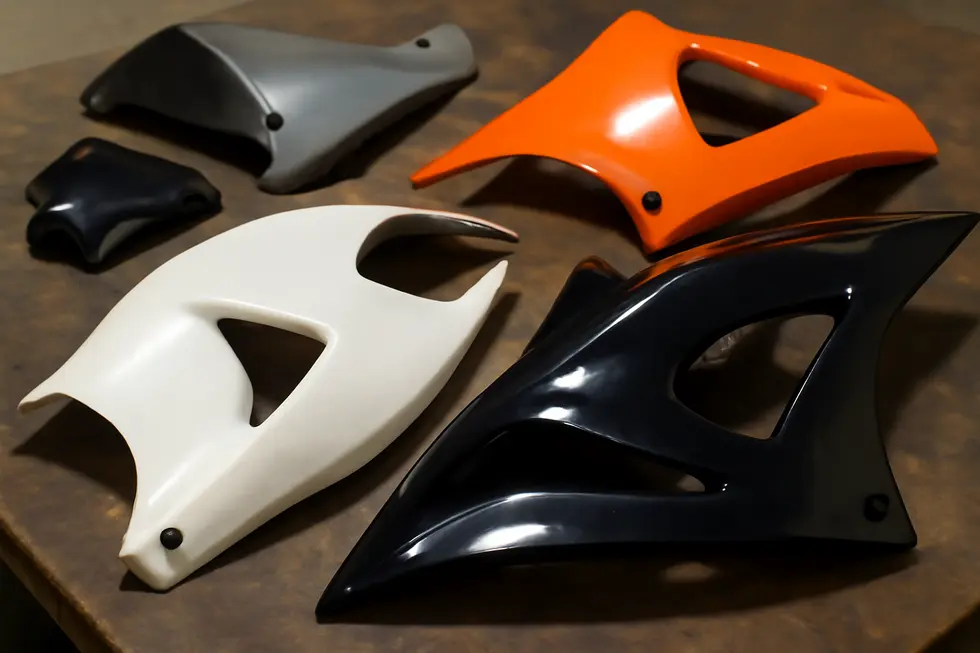 Different motorcycle fairing materials displayed on a workshop bench, showcasing the key substrates for painting.