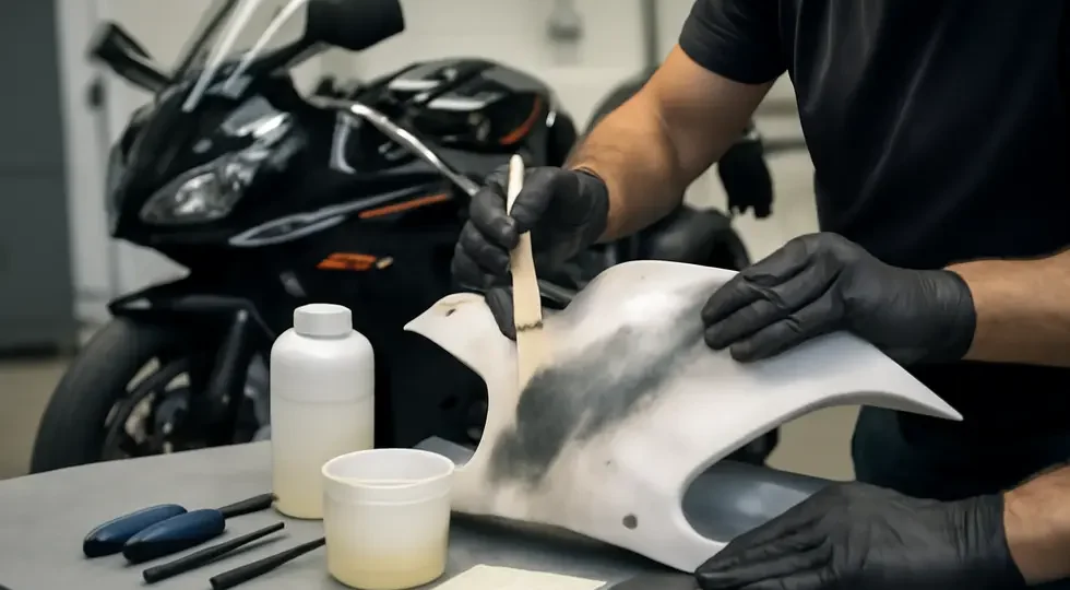 Professional motorcycle fairing repair underway using fiberglass techniques in a bright, detailed workshop environment.