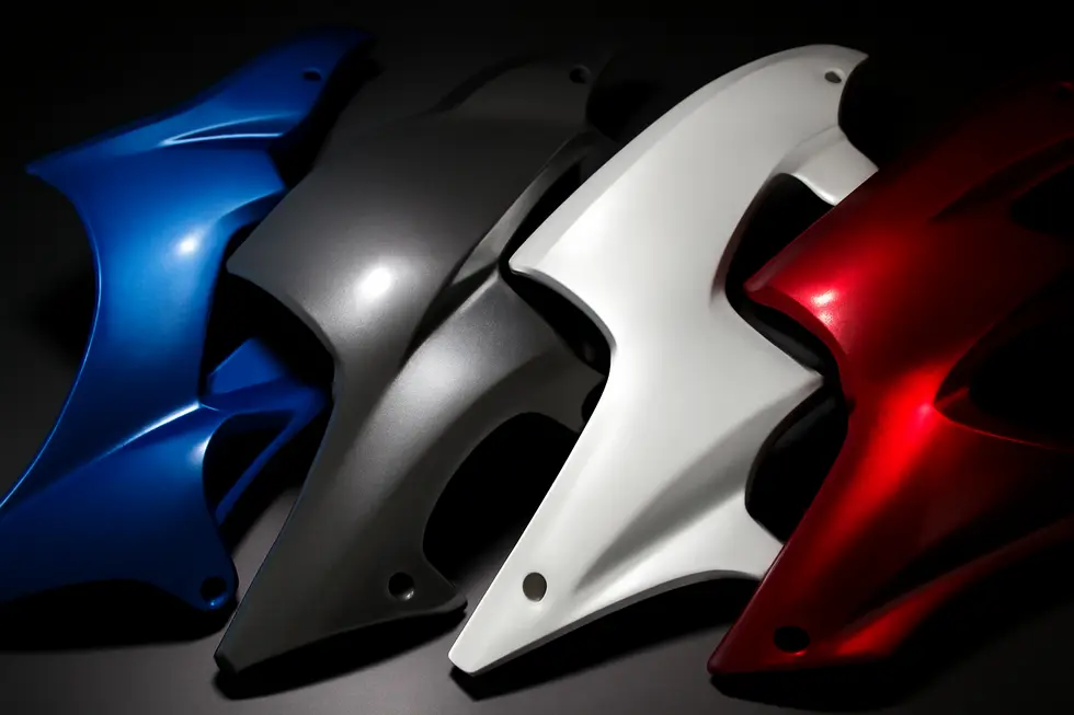 Showcase of various urethane and high-temperature paints used for motorcycle fairings in a workshop environment.