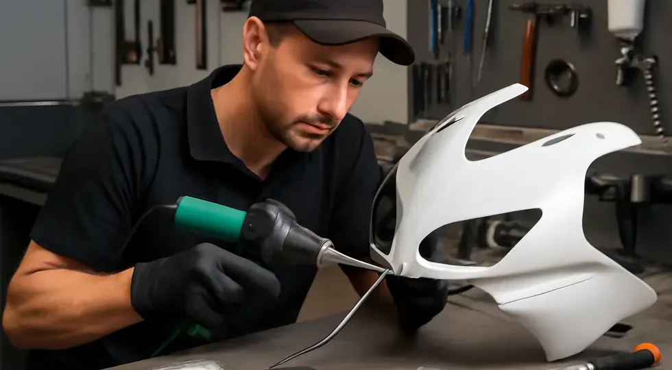A skilled mechanic repairing a cracked motorcycle fairing using plastic welding, fiberglass reinforcement, and finishing techniques.