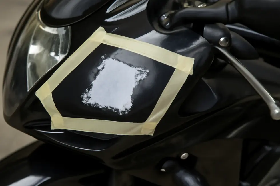 Utilizing controlled heat application to safely loosen sticker adhesive on a motorcycle fairing.
