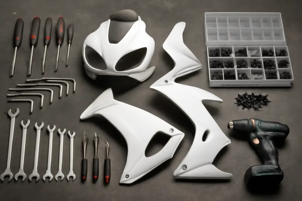 A mechanic meticulously unscrews bolts and detaches clips to remove old motorcycle fairings without causing damage.