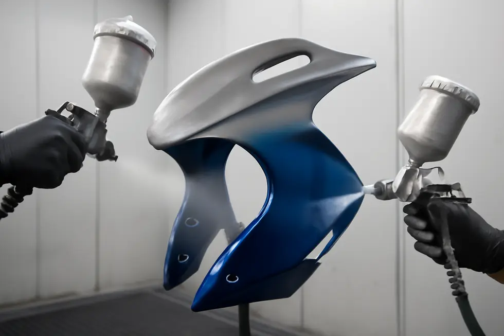 A specialized body shop showcasing technicians preparing and painting motorcycle fairings with precision.
