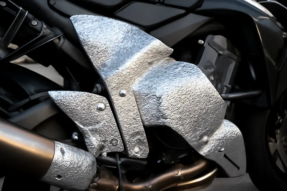 Foil-coated fiberglass and aluminum heat shields shielding motorcycle fairings from engine and exhaust heat.
